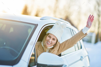 Ecstatic woman riding automobile in snowy winter