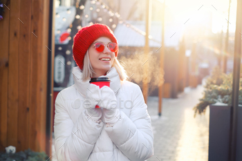 Girl in sunglasses drinks coffee from a cup exterior at a cafe