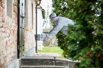 deliveryman in keeping swimsuit with a pizza advance a door