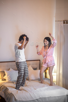 Man and lady in pajamas dancing on mattress