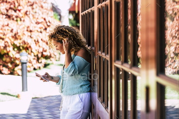 Standing adult girl open air home in the backyard ship message and read from cell phone