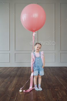 Child taking half in with a pink balloon and reproduction dwelling