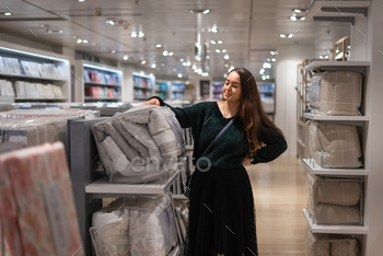 Feminine customer selecting quilt in shop