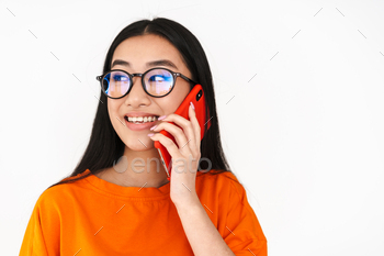 Asian elated student girl speaking on smartphone and smiling