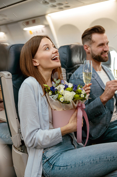 Joyful lady and man drinking champagne in airplane