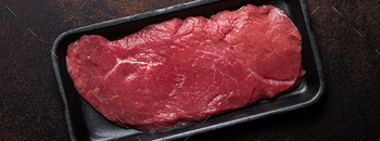 Pork lean uncooked fillet steak in shadowy plastic container