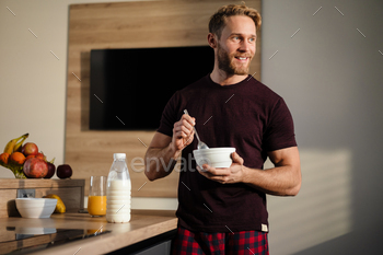 Comely healthy young man having tasty breakfast