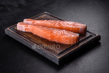 Contemporary salmon fillets on sunless slicing board with herbs and spices