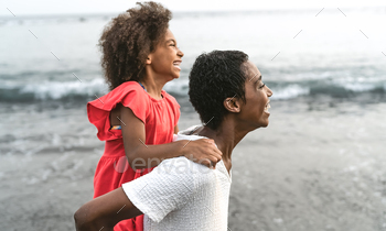 Entirely chuffed Afro mother and daughter having fun on the seashore all over holidays