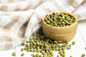 Dried green peppercorn. Dry green pepper spice in bowl on white table.