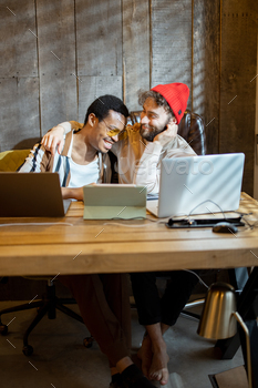 Homosexual couple working on computer programs at home place of industrial