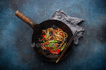 Asian lumber fry noodles with greens in black wok pan