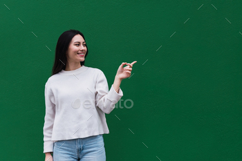 Asian woman feeling chuffed and smiling, having a peek to an object or thought held on the hand on the sid