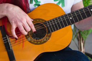 Crop girl taking half in Spanish guitar