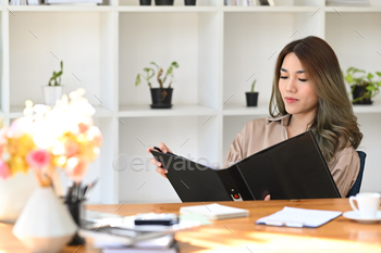 Industry girl entrepreneur checking financial file at her predicament of business.