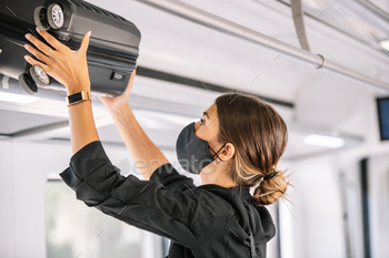 Lady in cowl placing suitcase on shelf