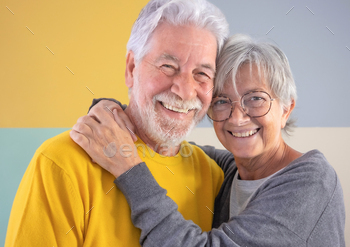 Elegant caucasian senior couple standing over isolated spellbinding background hugging with savor