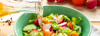 Unique vegetable salad with olive oil in ceramic bowl on a wood background.