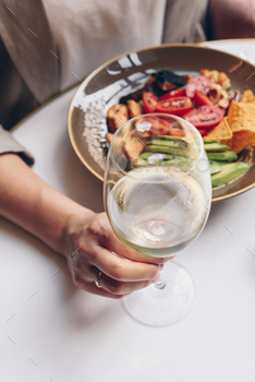 Lady having her lunch and she is retaining glass of white wine