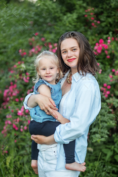 Mom holds toddler daughter in her hands. Unruffled hugs of mom. Leisure in the park in the spring.