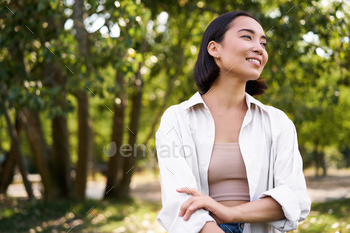 Image of korean lady walking in park, smiling while having a awake stroll in woods