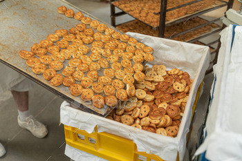 The baker areas the recent salted pretzels taken out of the oven.Trays with many pretzels