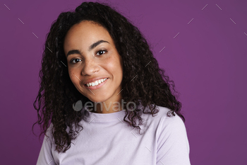 Younger black girl with wavy hair smiling and having a note at camera