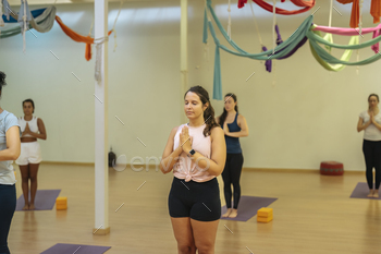 young lady with eyes closed doing samasthiti pose in a yoga class