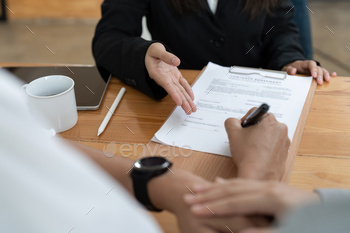 Younger couple signing contract agreement with exact estate agent.