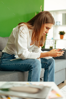 Younger girl sitting on the couch and the exercise of her smartphone