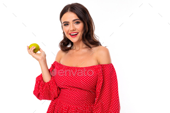 Pretty younger girl with perfect smile, shades and holds a inexperienced apple and smiles, isolated on