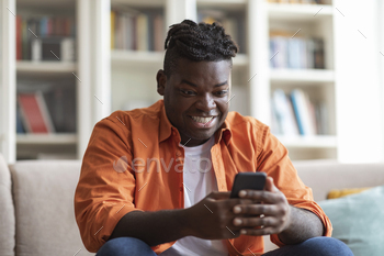 Smiling african american man the usage of cell phone at house