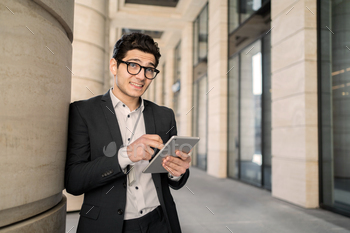 A manager with glasses uses a tablet goes to the establish of job in a substitute suit, smiles and thinks about