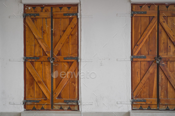 Wooden shutter doors on an ragged white wall