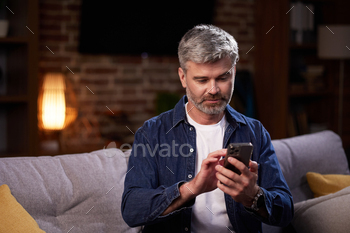 Smiling man communicates on-line in social networks and uses a smartphone. A man in casual garments