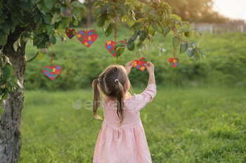 Child decorates branches with hearts cards with multicolored puzzle on  autism day