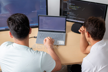 Two younger programmers in an place of work, preoccupied as they work on a programming and skills project