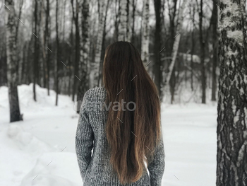 Young Girl with Long Hair Standing in Front of Winter Woodland