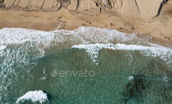 Aerial phrase of ocean waves breaking on a sandy seaside. Nature background