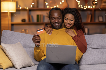 Chuffed shadowy enthusiasts hunting from home, the utilization of laptop, bank card