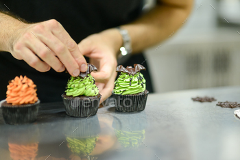 pastry chef baker preparing halloween green orange monster cupcakes handmade