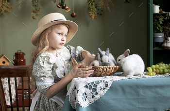 woman with long blond hair with gray rabbits at dwelling. spring day and overjoyed Easter