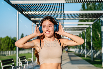 Carefree woman listening to songs in headphones in park