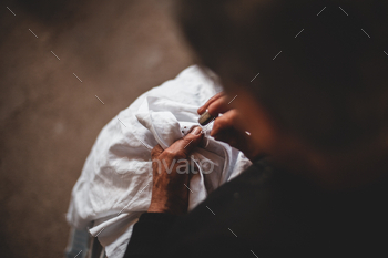 Female holds a needle in her fingers and embroiders a sample with white threads on a white cloth