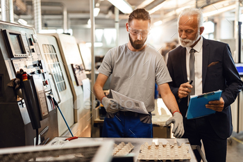 Senior positive contemplate an eye fixed on inspector and younger employee cooperating in a factory plant.