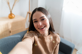 Smiling woman sitting on couch taking a selfie