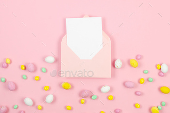 Colourful sweet easter eggs on pastel crimson background and crimson envelope with blank card