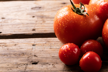 Finish-up of fresh red tomatoes with water drops on wooden desk