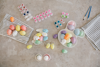 Holiday Easter preparations: handmade colored eggs, paints and brushes on a table.