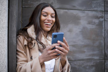 Comfy african girl smiling whereas the usage of the cell out of doorways